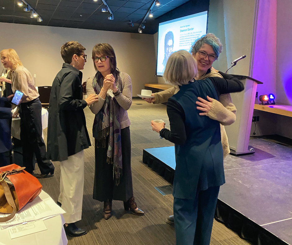 WeMB Business Breakfast attendees are hugging and chatting